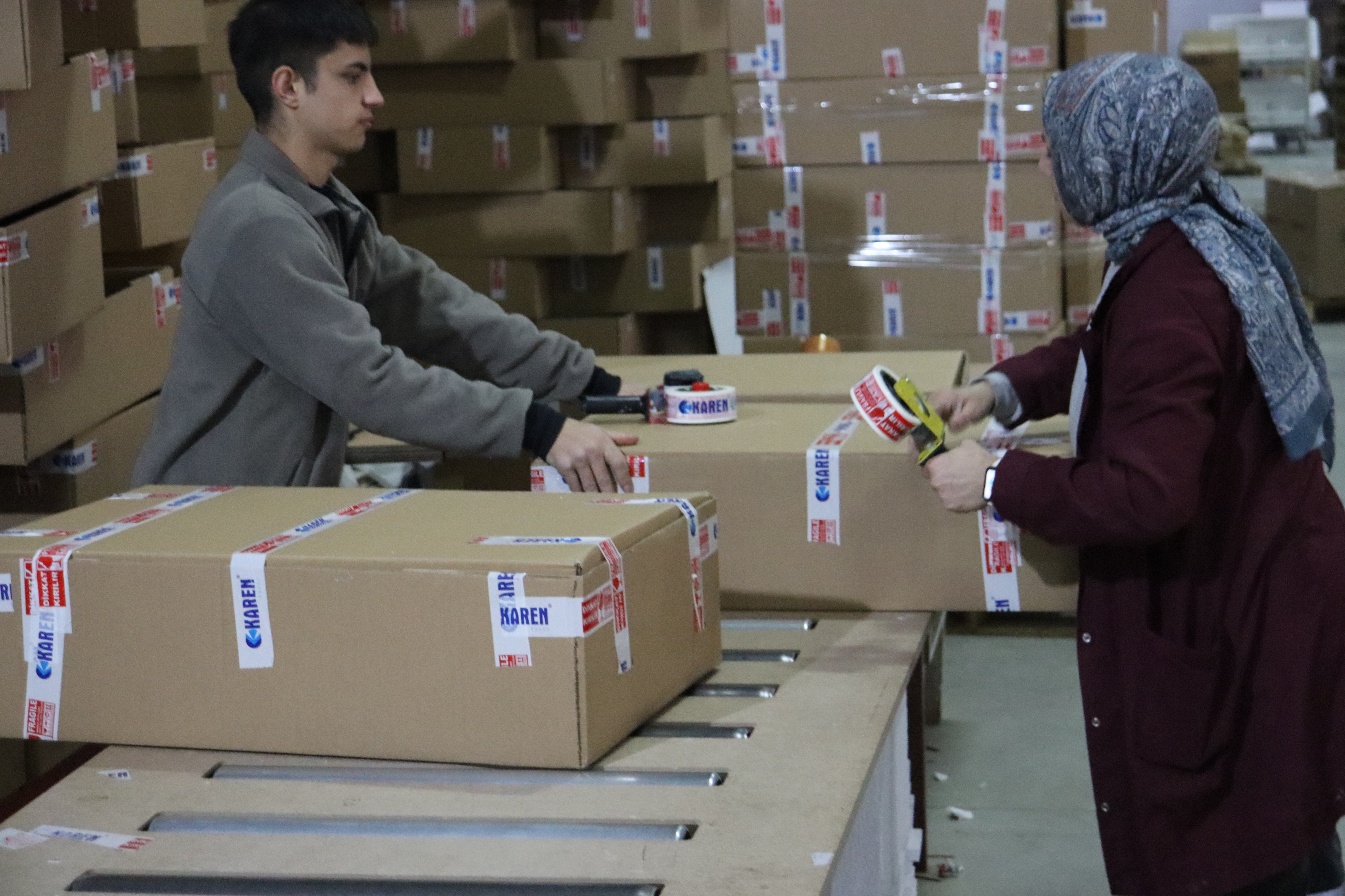 Mitarbeiter verpacken fertige Badmöbel-Kartons für den Versand