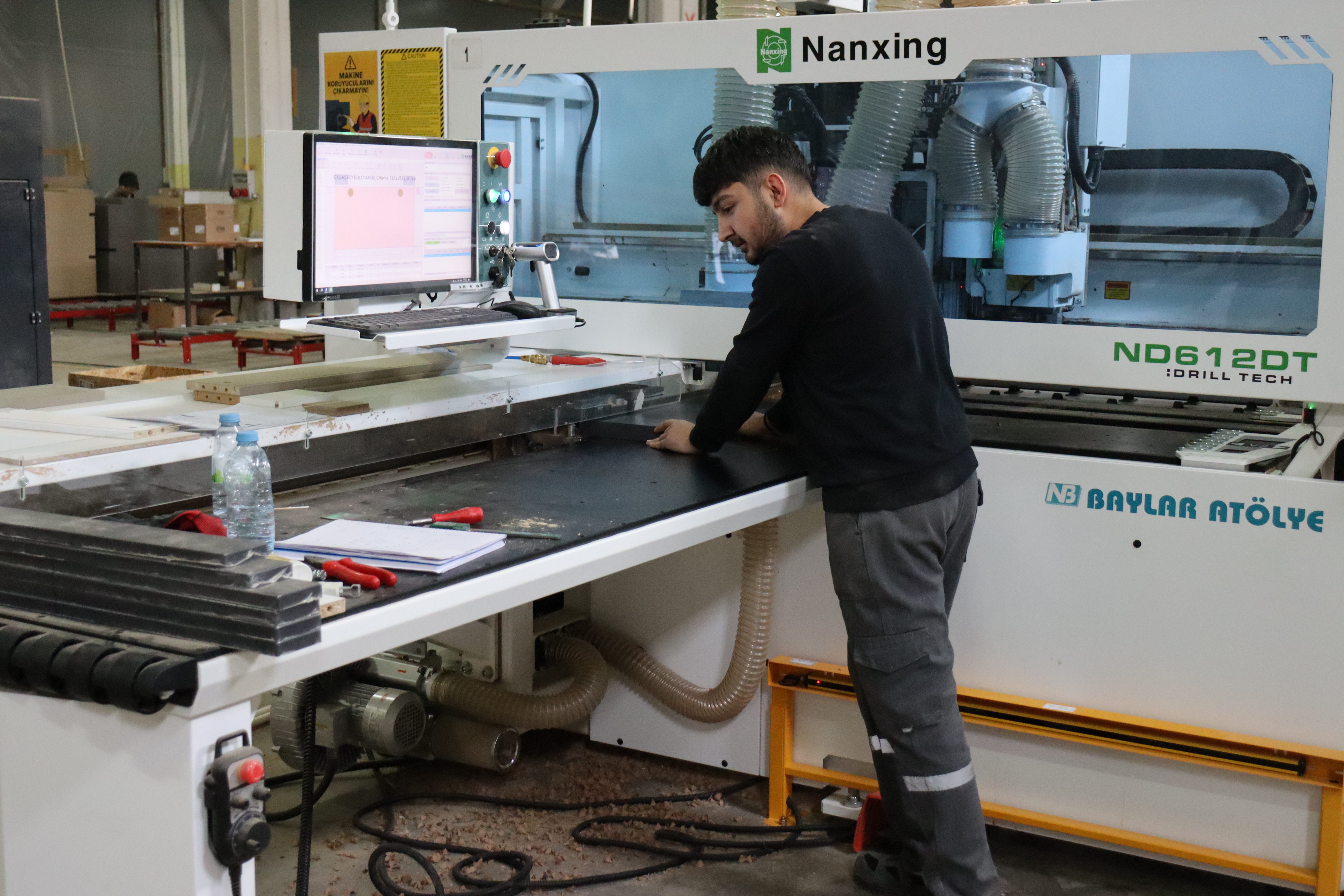 Mitarbeiter kontrolliert CNC-Bearbeitung am Steuerungsbildschirm